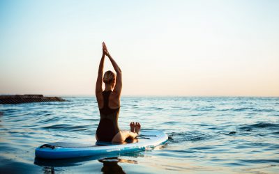 Silhouette of beautiful girl practicing yoga on surfboard at sunrise. Silhouette of young beautiful girl practicing yoga on surfboard in sea at sunrise.